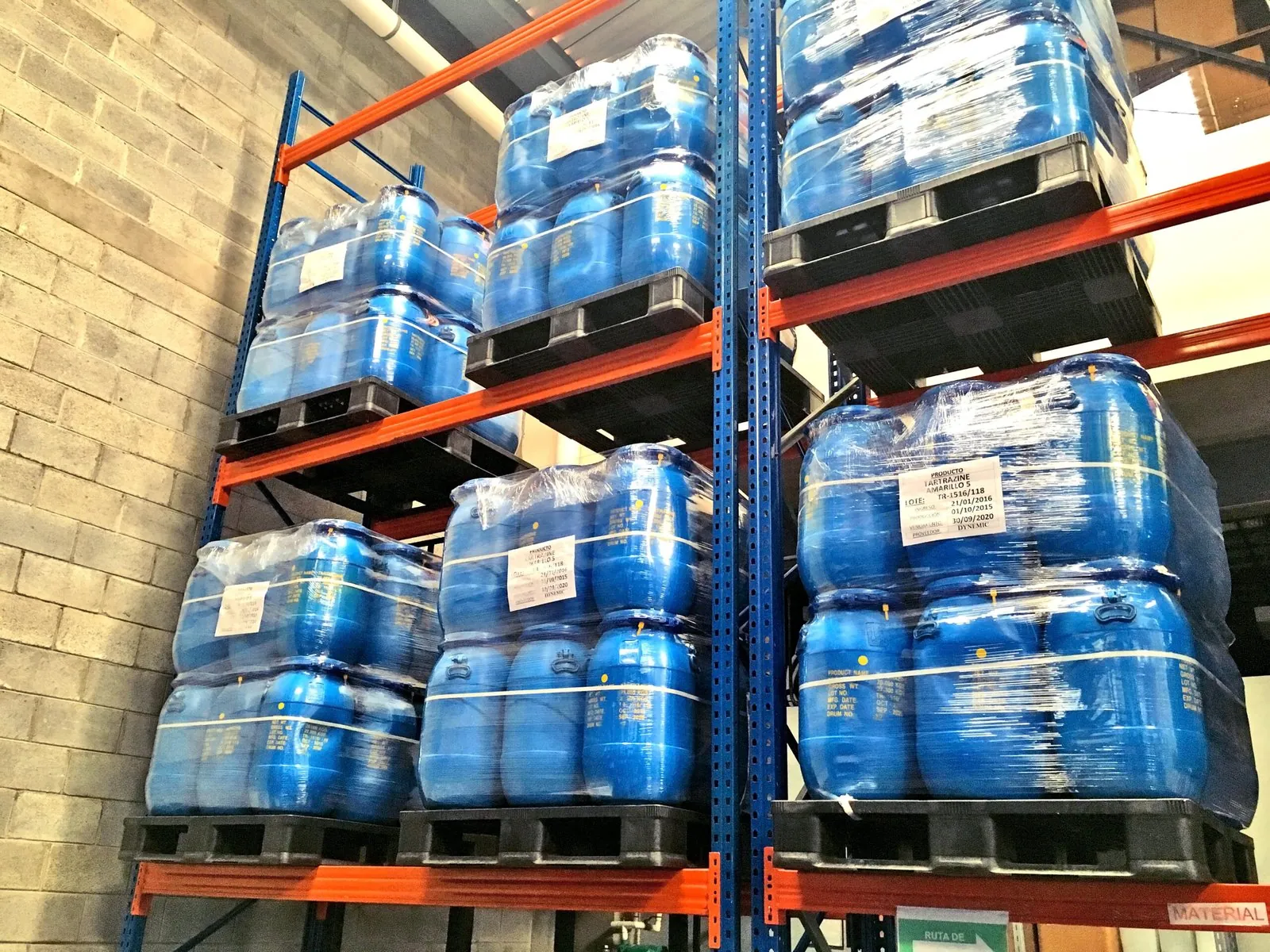 Tambos de insumos sobre pallets plásticos en rack